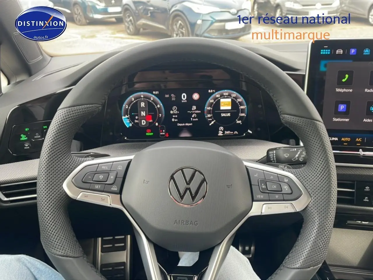 Vue intérieure centrée sur le volant noir perforé de la Volkswagen Golf 2026 avec tableau de bord numérique et écran tactile.