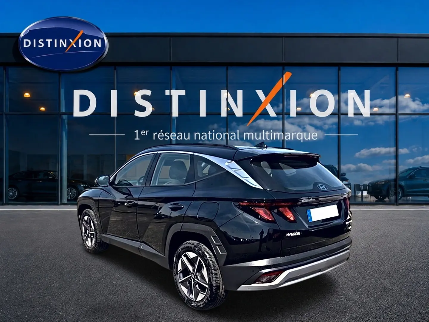 Vue 3/4 arrière droite d’un Hyundai Tucson noir 2026 garé devant une vitrine avec logo Distinxion.