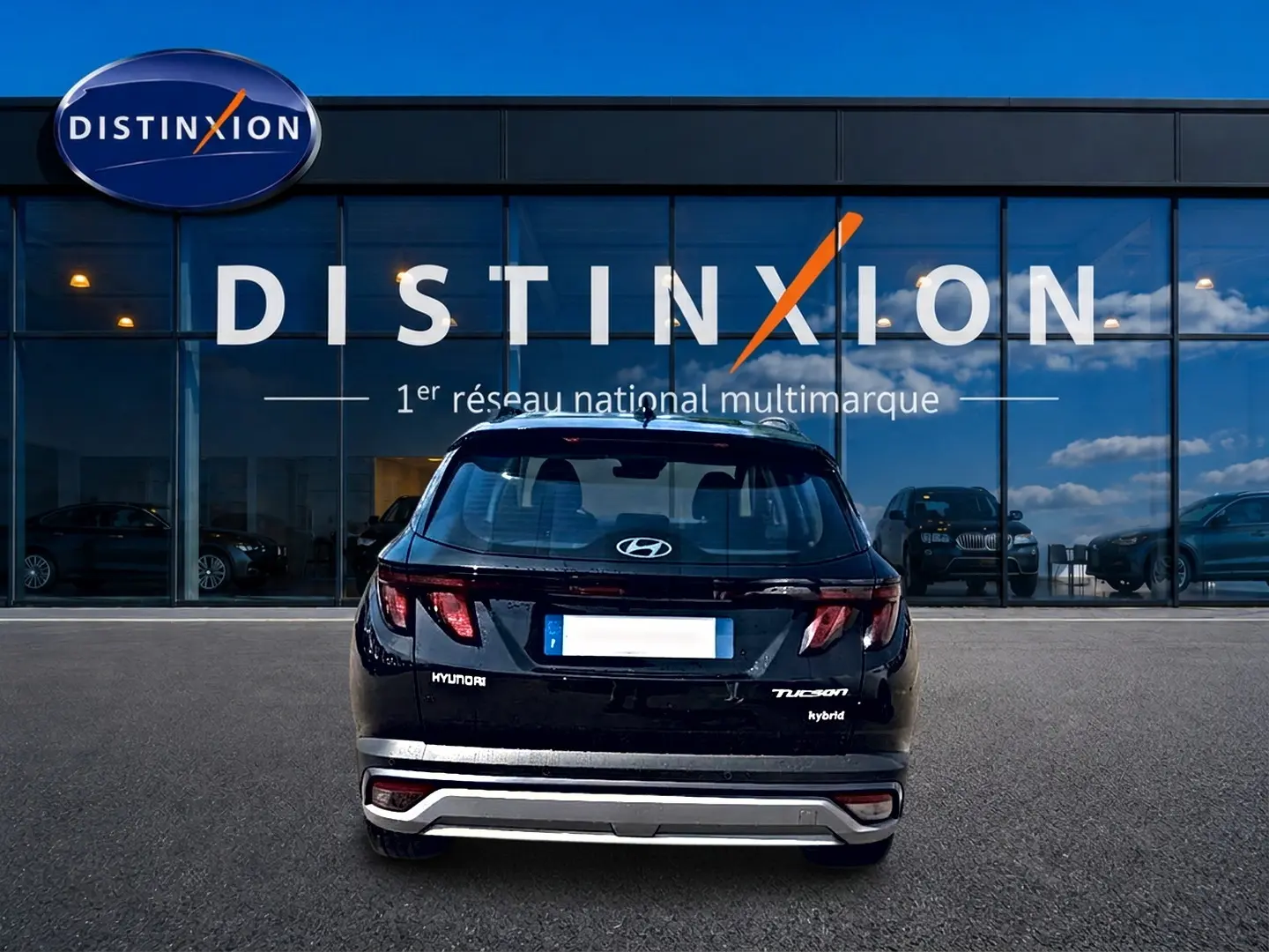 Vue arrière d'un Hyundai Tucson noir hybride garé devant une vitrine avec logo Distinxion.