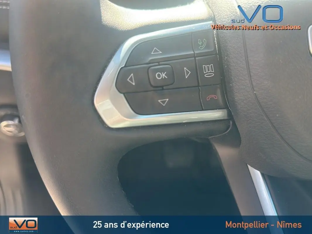 Gros plan sur les commandes au volant du Jeep Compass noir 2023, mettant en valeur les boutons multifonctions.