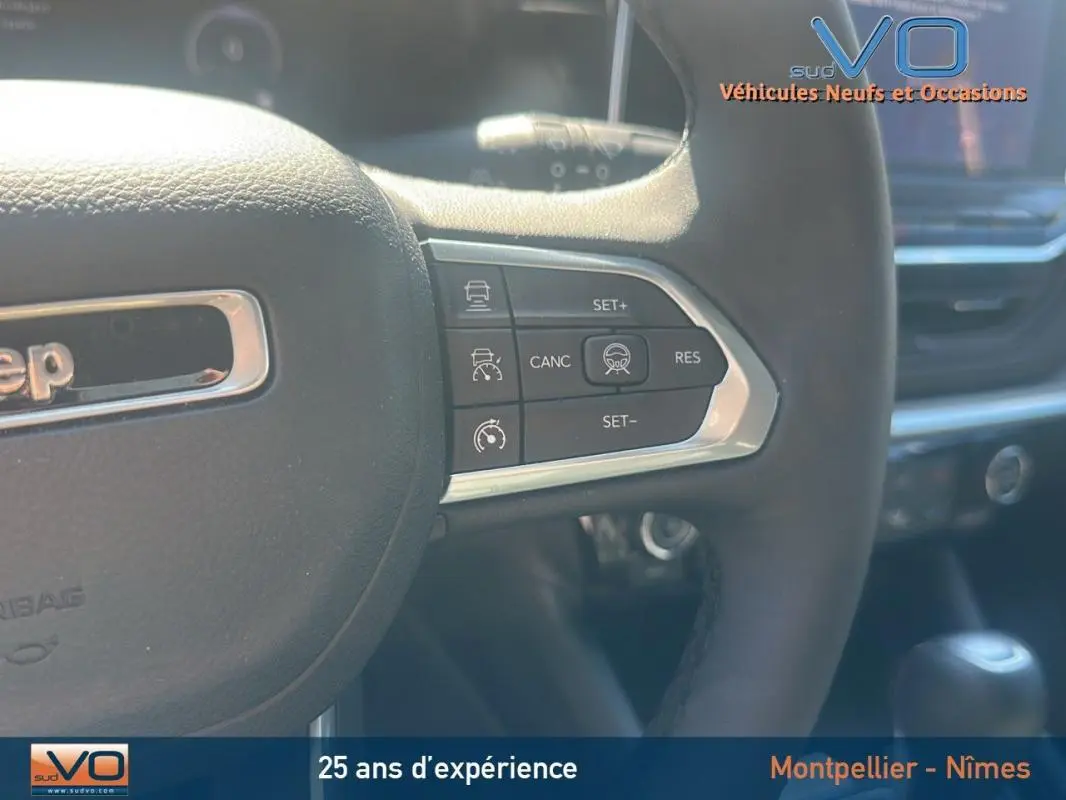 Gros plan sur le volant noir du Jeep Compass 2023 Limited avec commandes de régulateur de vitesse intégrées.