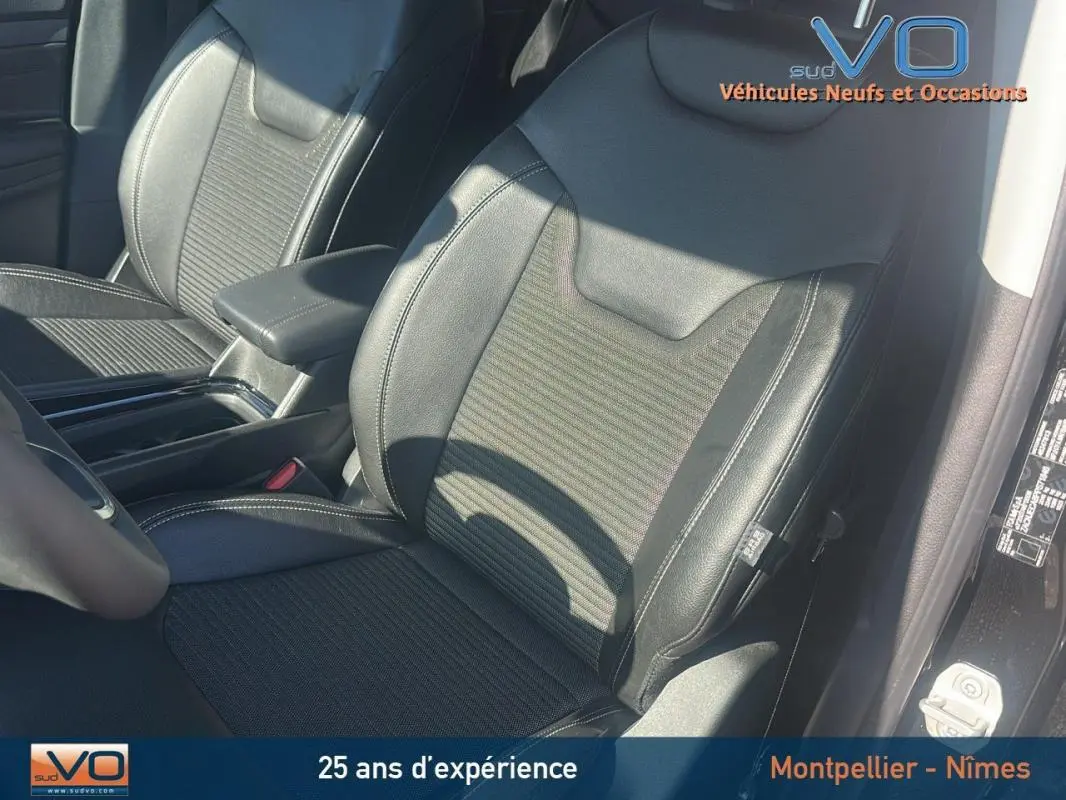 Gros plan sur les sièges avant noirs en cuir et tissu du Jeep Compass 2023 avec accoudoir central visible.