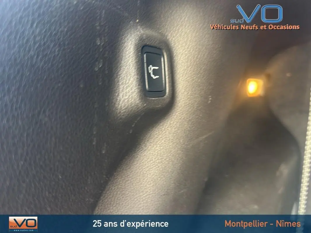 Bouton d'ouverture du hayon intérieur sur un Jeep Compass noir 2023, vue rapprochée du coffre.