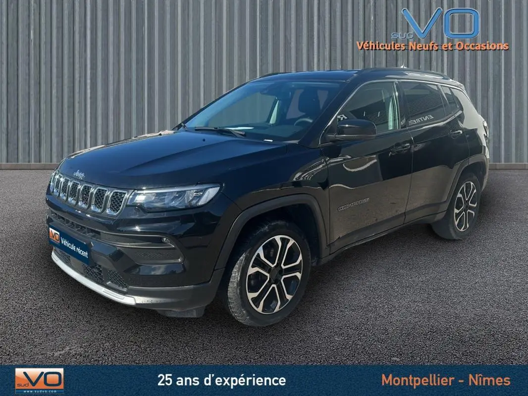 Jeep Compass noir en 3/4 avant droit, avec barres de toit et jantes 18 pouces visibles sur fond urbain.