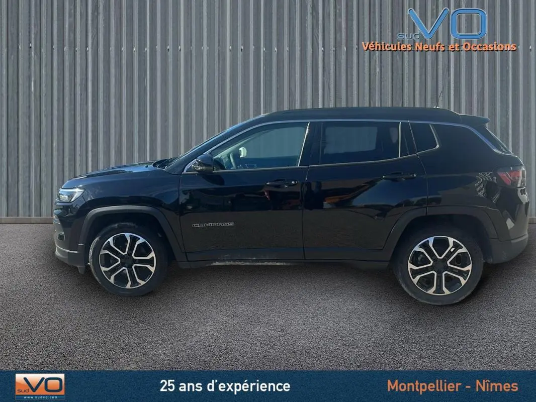 Profil côté gauche d'un Jeep Compass noir 2023 avec jantes 18 pouces, barres de toit et rétroviseurs électriques rabattables.