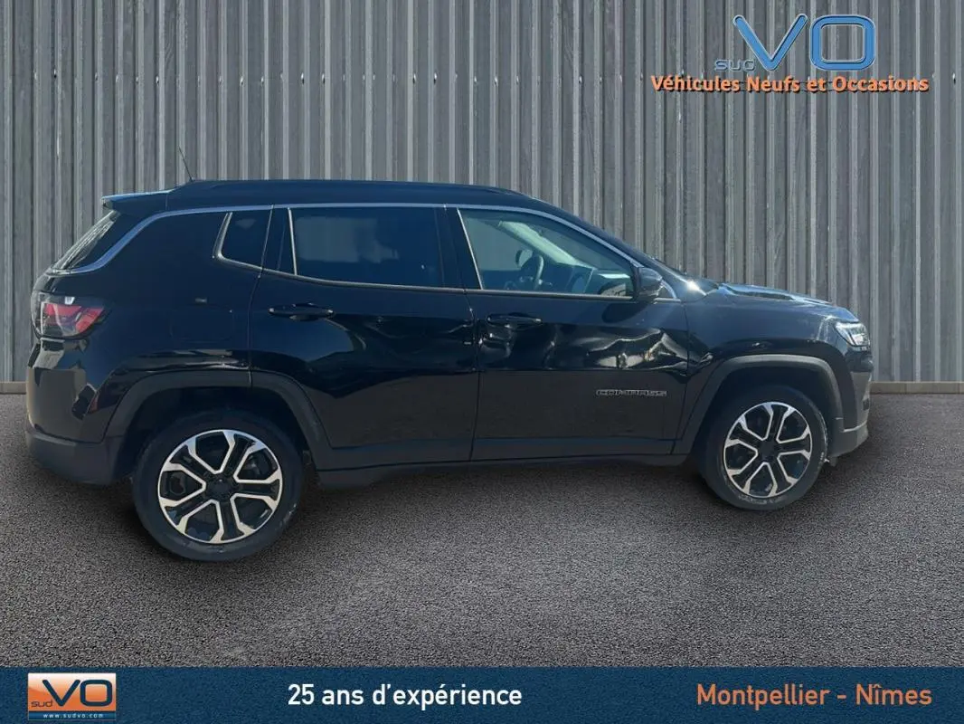 Profil latéral gauche du Jeep Compass noir 2023 avec jantes 18 pouces et barres de toit visibles.