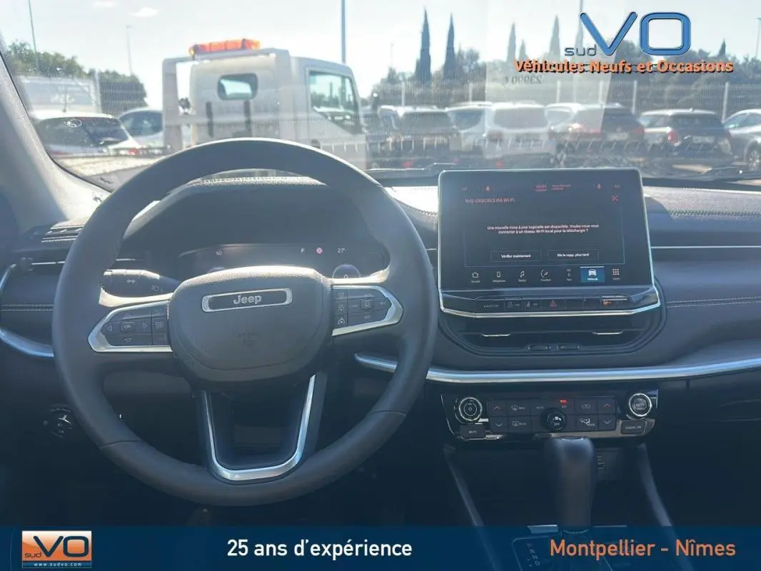 Vue intérieure frontale du tableau de bord et volant noir du Jeep Compass 2023 avec écran tactile et commandes intégrées.