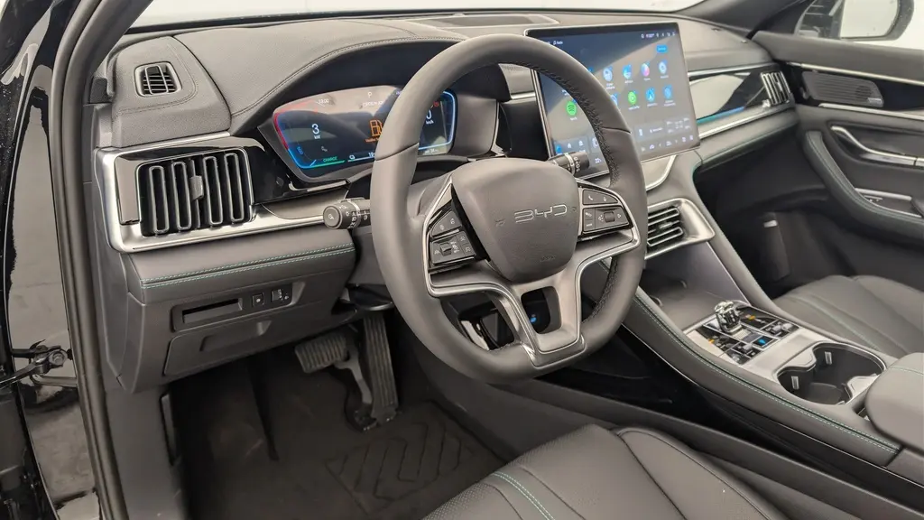 Vue intérieure côté conducteur du BYD SEAL U 2025 noir, avec volant multifonction, tableau de bord numérique et écran tactile central.