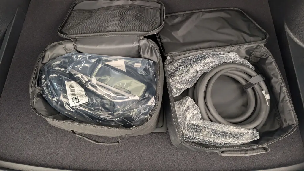 Gros plan sur les câbles de recharge dans des sacs noirs ouverts, posés dans le coffre d’un BYD SEAL U Obsidian Black.