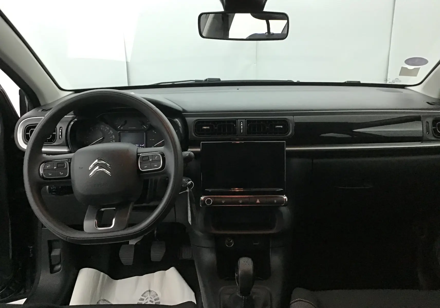 Vue frontale de l’intérieur noir de la Citroën C3 2022 avec volant multifonction et écran tactile central.