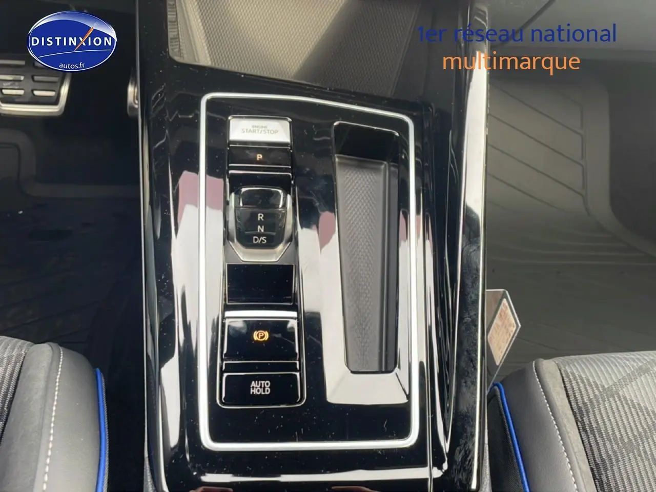 Vue plongeante sur la console centrale noire brillante de la Volkswagen Golf 1.5 eTSI R-Line avec sélecteur de boîte auto.