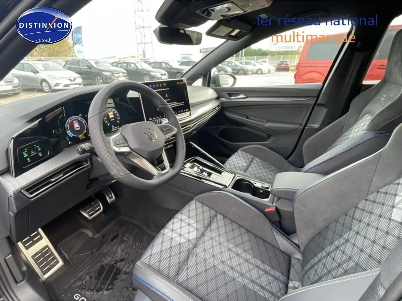 Vue intérieure côté conducteur de la Volkswagen Golf 2026 avec sièges sport gris à motif tartan et volant cuir multifonction.