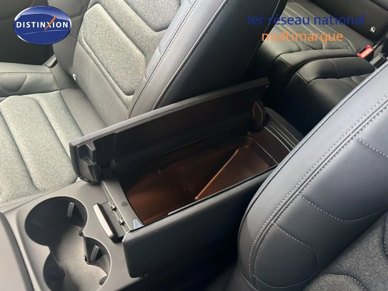Gros plan intérieur sur la console centrale ouverte et les sièges tissu et cuir noir du Citroën C5 Aircross 2025 hybride.