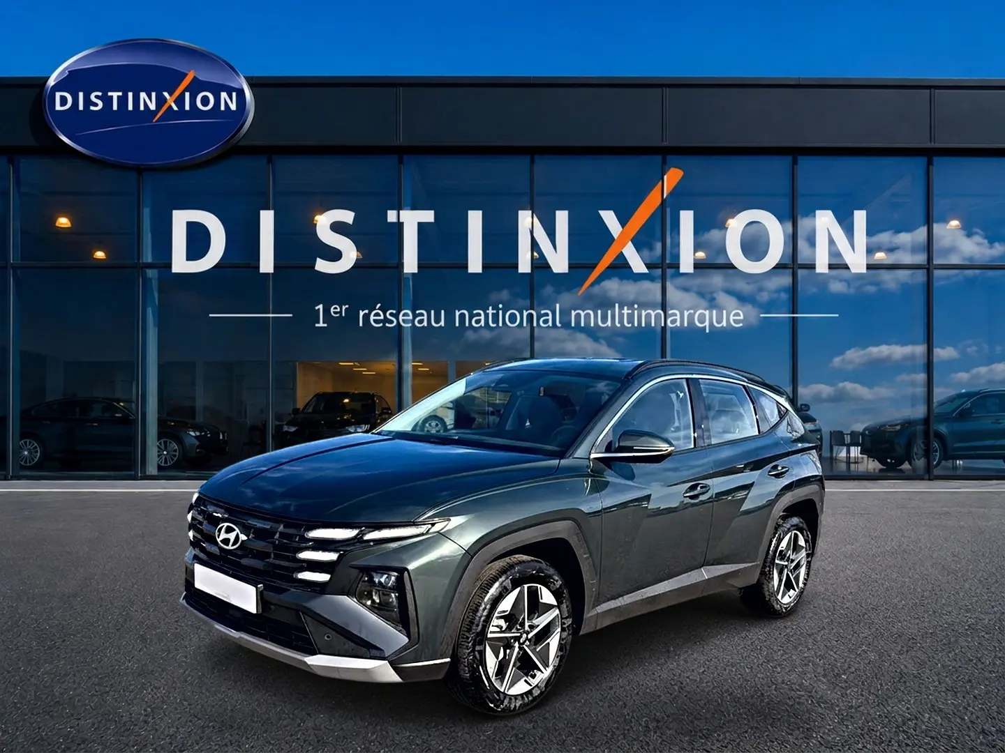 Hyundai Tucson 1.6 t-gdi 239 hybride vert en 3/4 avant droit devant un showroom Distinxion.