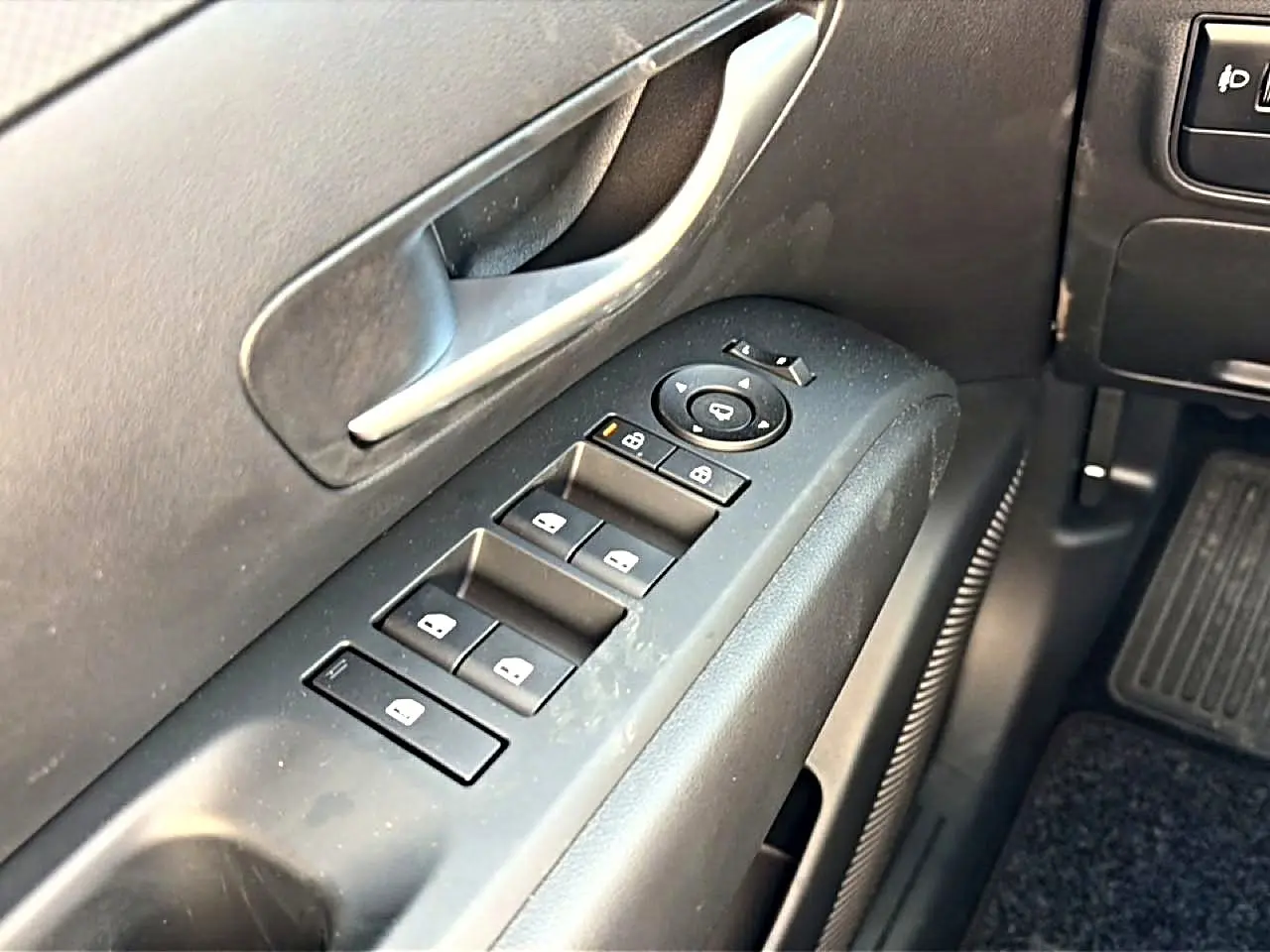 Détail des commandes de vitres et rétroviseurs côté conducteur du Hyundai Tucson 2026 intérieur noir.