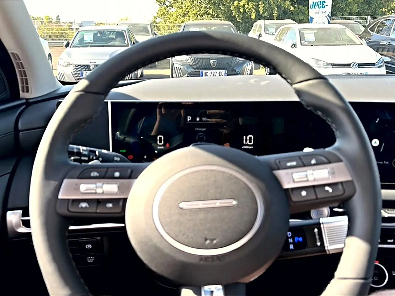 Vue intérieure centrée sur le volant cuir noir multifonction du Hyundai Tucson vert, avec tableau de bord digital en arrière-plan.