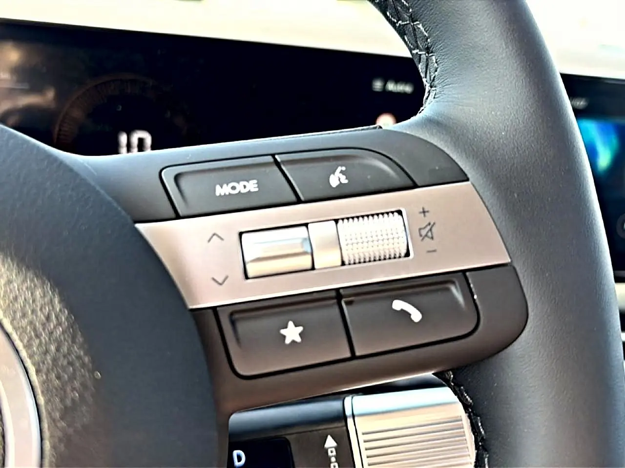 Gros plan sur les commandes audio au volant cuir noir du Hyundai Tucson 2026 hybride, avec molette de volume argentée.