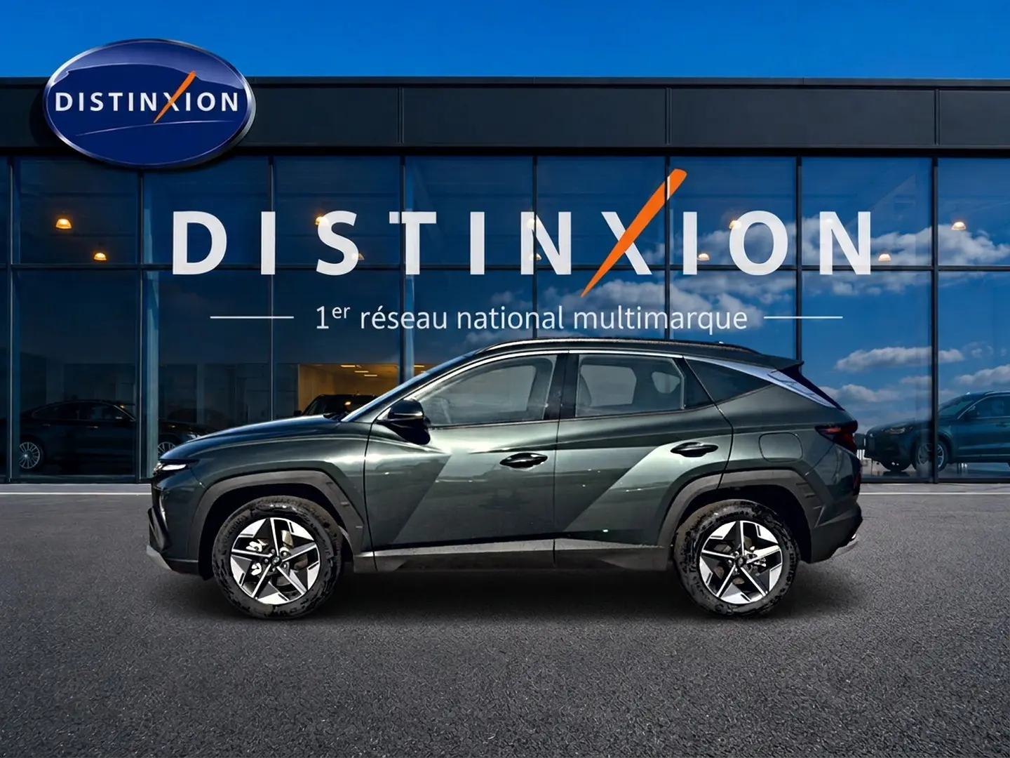 Vue latérale gauche du Hyundai Tucson 2026 vert métallisé avec jantes alliage 18 pouces devant une vitrine Distinxion.