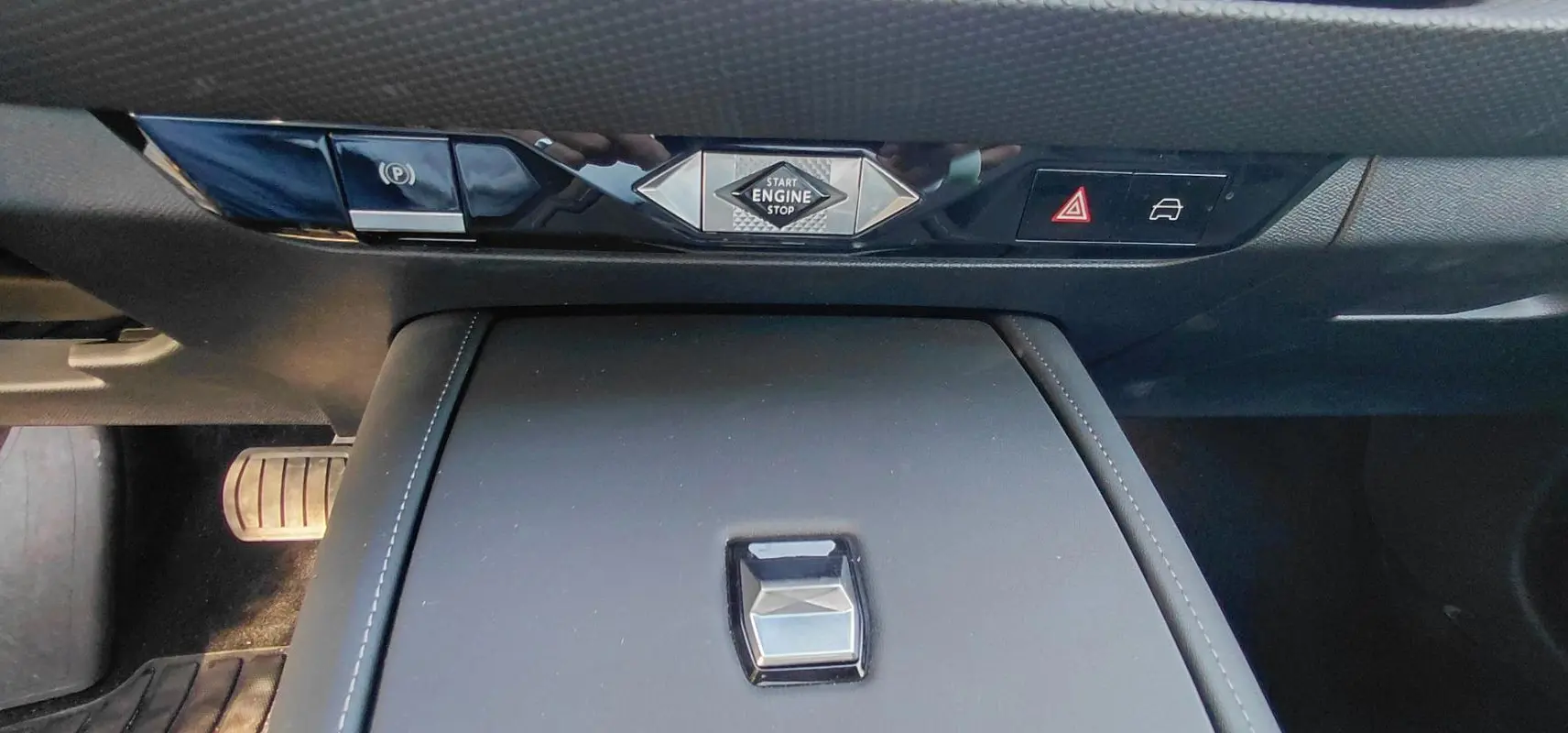 Vue rapprochée de la console centrale du DS4 2024 Hybride E-Tense avec bouton start engine et commandes noires brillantes.