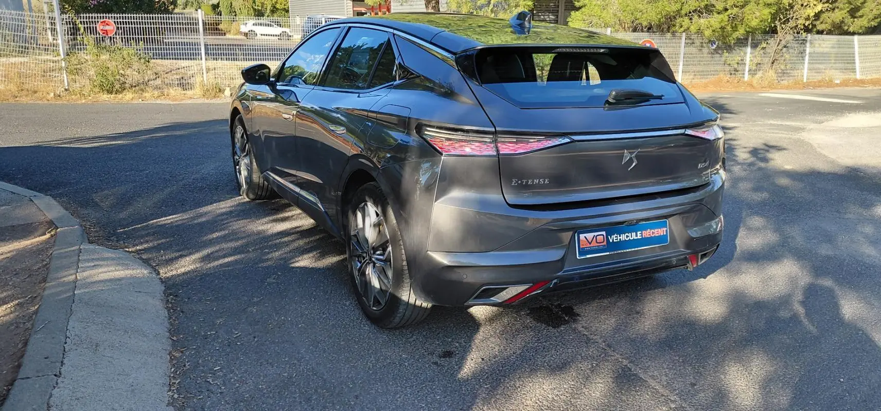 Vue 3/4 arrière droite d'une DS4 gris métallisé 2024, version Hybride E-Tense avec feux arrière effilés et logo DS distinctif.
