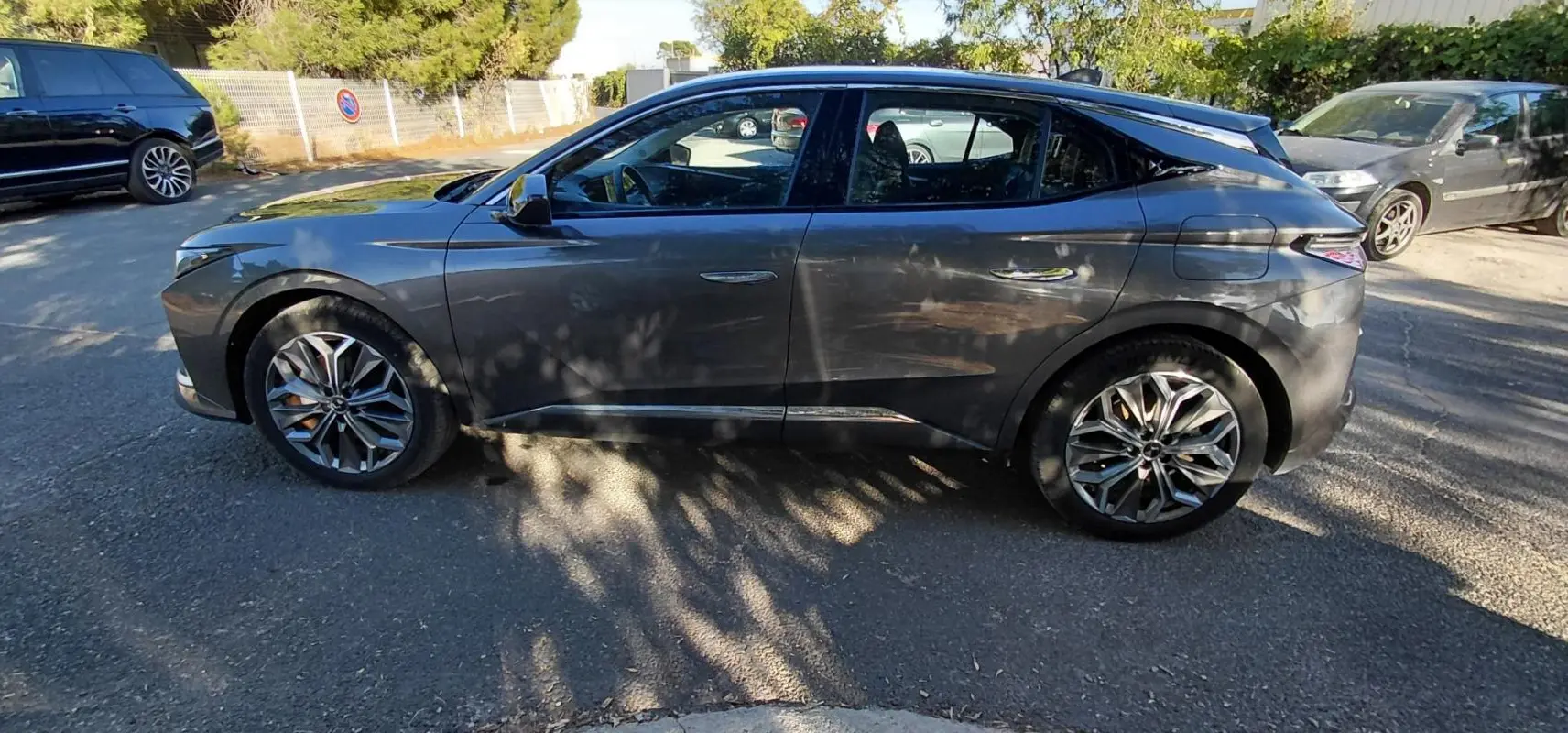 Vue de profil côté gauche d'une DS4 gris 2024 Hybride E-Tense avec jantes alliage et lignes sculptées distinctives.