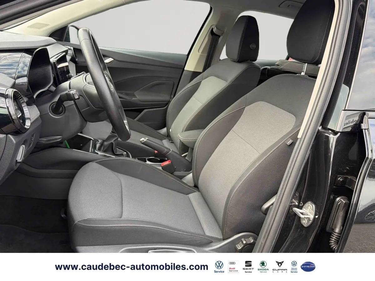 Vue intérieure côté conducteur de la Skoda Fabia noire 2025, sièges tissu gris et volant cuir multifonctions.