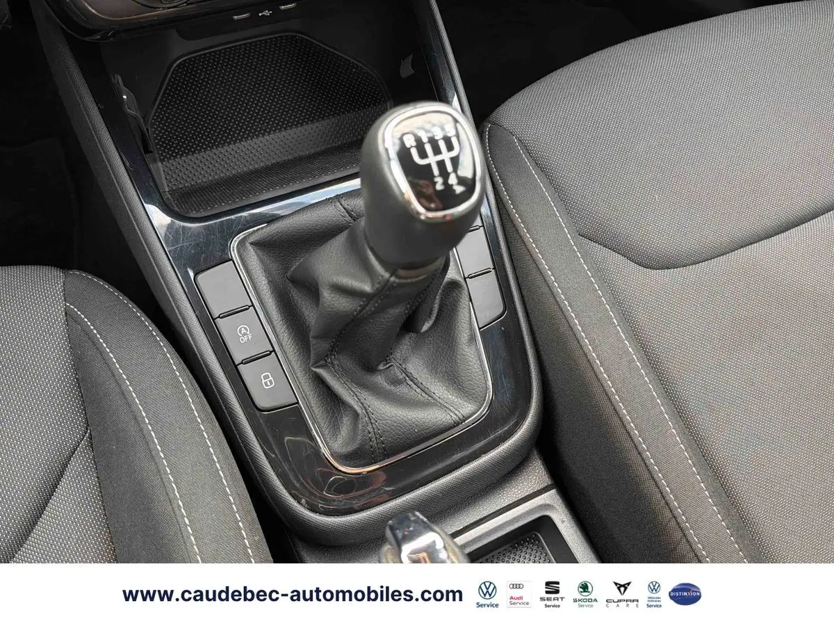 Gros plan sur la commande de boîte manuelle noire et les sièges tissu gris de la Skoda Fabia 2025.
