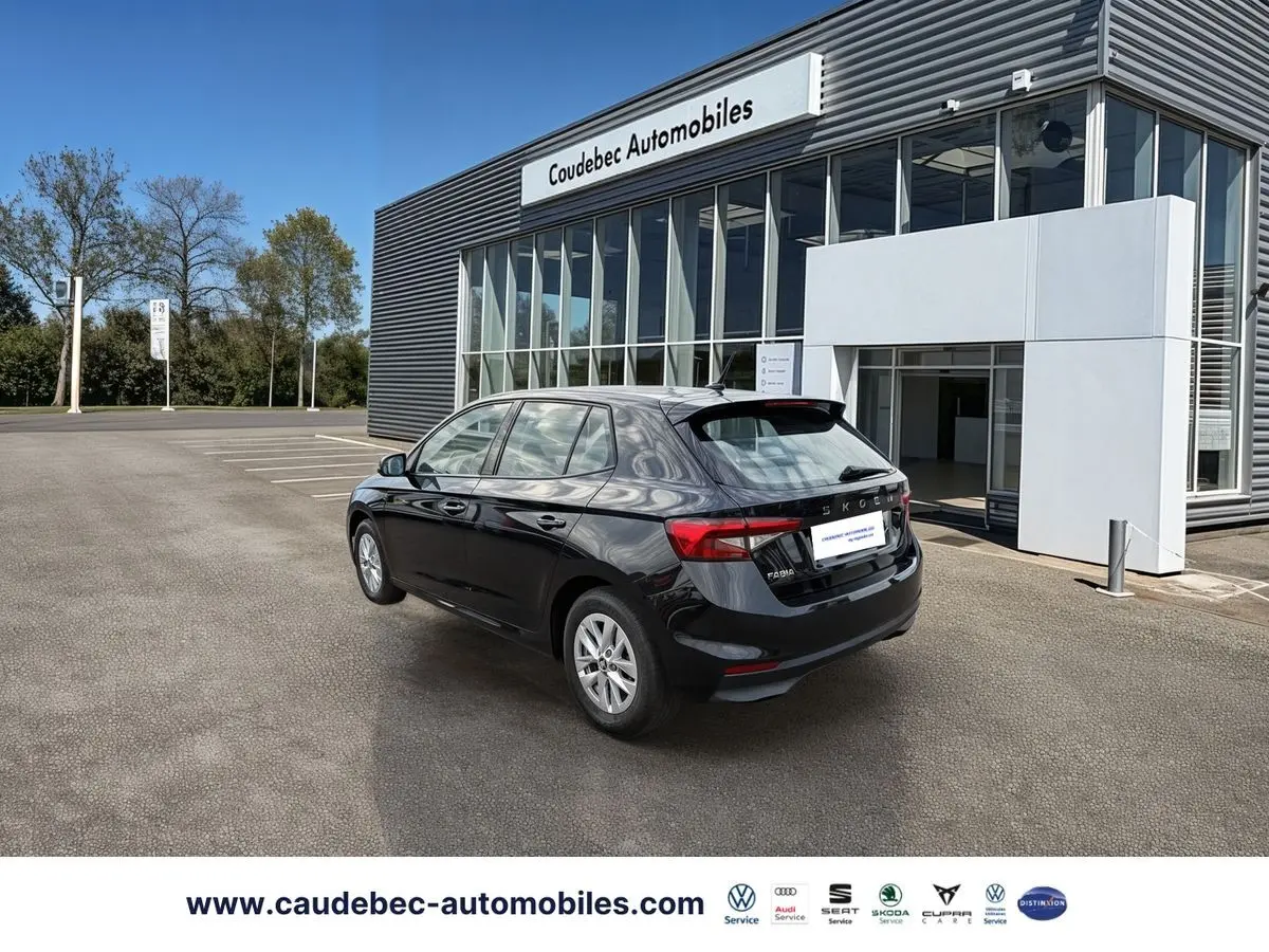 Vue 3/4 arrière droite d'une Skoda Fabia noire stationnée devant un bâtiment commercial moderne.