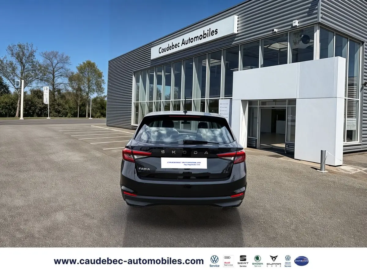 Vue arrière d'une Skoda Fabia noire 2025 stationnée devant un bâtiment moderne avec enseigne Caudebec Automobiles.