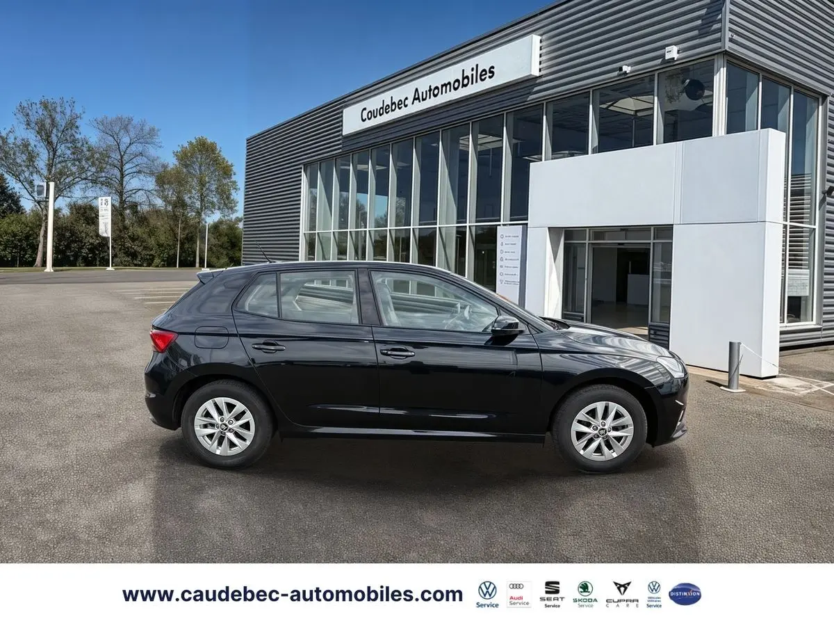 Vue de profil côté gauche d'une Skoda Fabia noire 2025 garée devant un bâtiment moderne de concession.