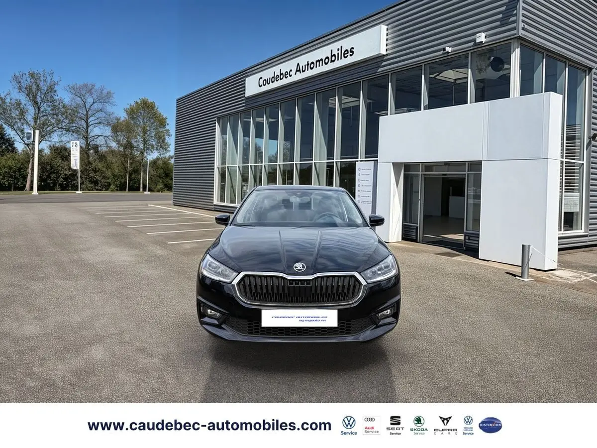 Vue frontale d'une Skoda Fabia noire 2025 stationnée devant un bâtiment moderne de concession automobile.