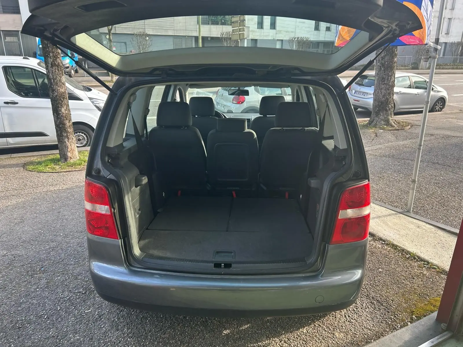 Vue arrière d'un Volkswagen Touran gris 2004 avec coffre ouvert et sièges arrière visibles.