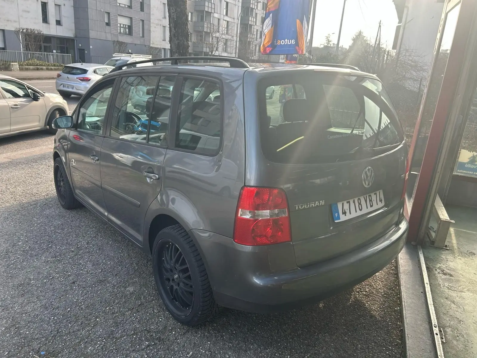 Volkswagen Touran gris 2004 vu en 3/4 arrière droit, avec jantes noires et toit ouvrant visible.