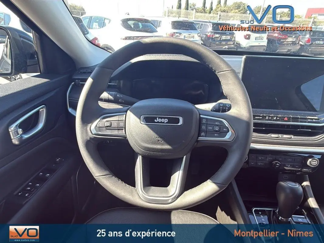 Vue intérieure centrée sur le volant Jeep Compass gris 2023 avec tableau de bord et écran tactile visible.