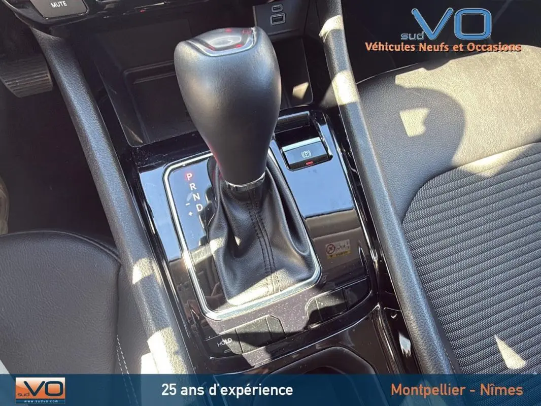 Gros plan sur la console centrale du Jeep Compass gris 2023, mettant en valeur le levier de vitesses automatique et l'accoudoir central.