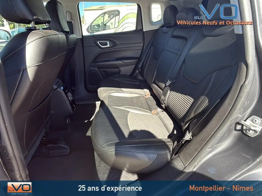 Vue intérieure arrière droite du Jeep Compass gris 2023 montrant les sièges arrière en cuir et tissu avec accoudoir central.
