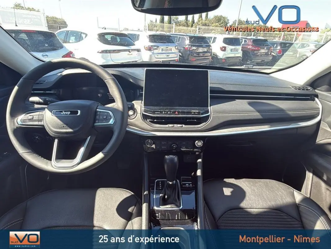 Intérieur du Jeep Compass 2023 vu de face, tableau de bord noir avec écran tactile central et volant multifonction.