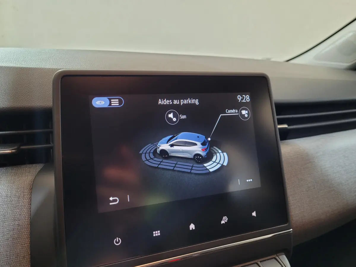 Écran tactile central de la Renault Clio gris foncé affichant l'aide au parking avec vue 3D du véhicule.