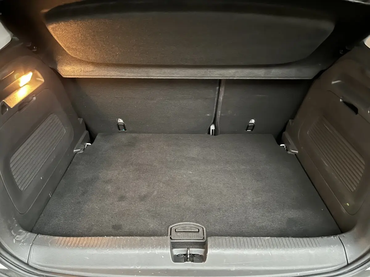 Vue du coffre arrière noir de l’Opel Crossland X blanc, montrant l’espace de chargement avec plancher plat et éclairage intérieur.