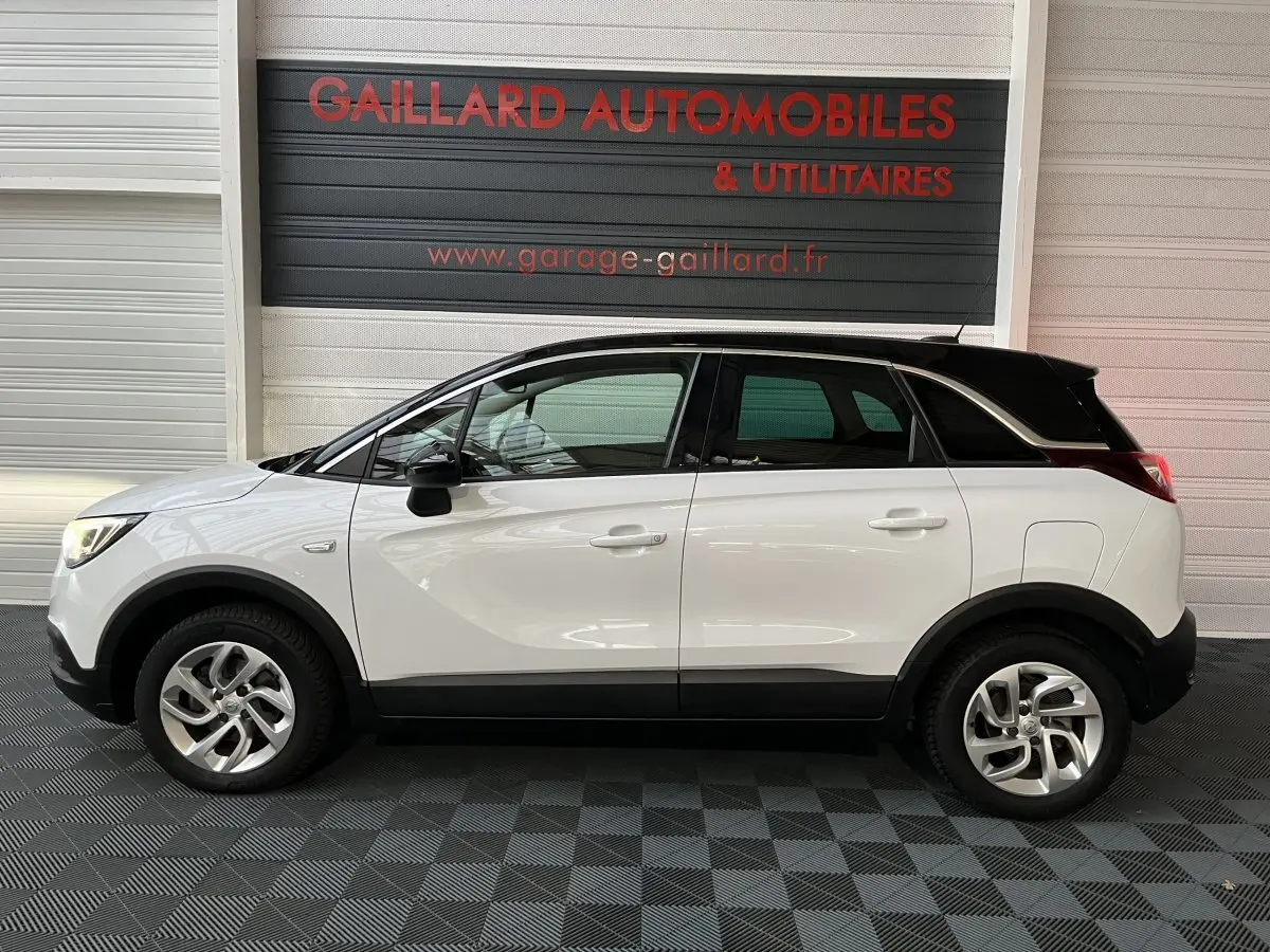 Opel Crossland X blanc vue de profil côté gauche, toit noir contrastant et jantes alliage visibles.
