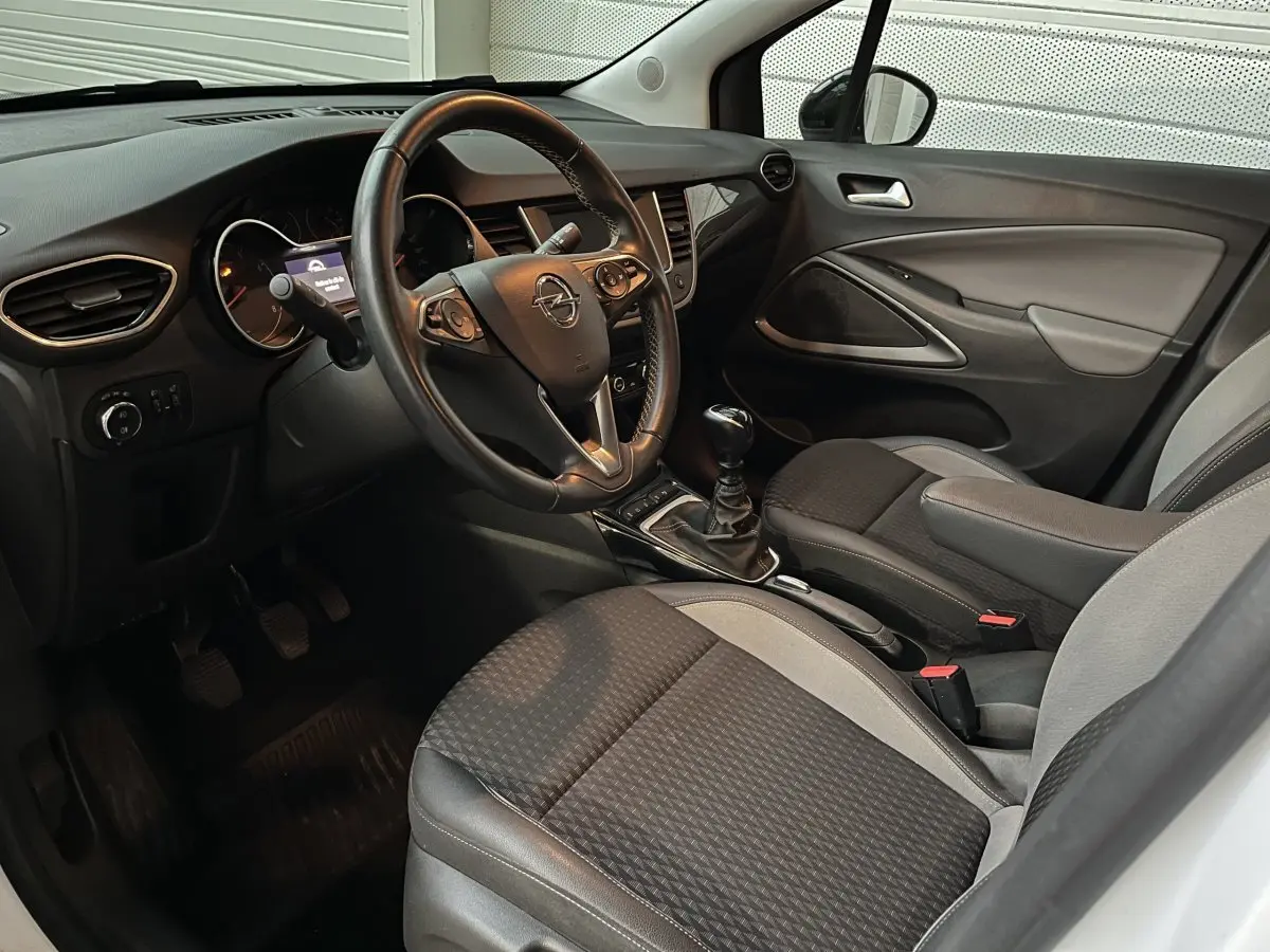 Intérieur avant droit de l’Opel Crossland X blanc, volant cuir, boîte manuelle et sièges tissu bicolores.