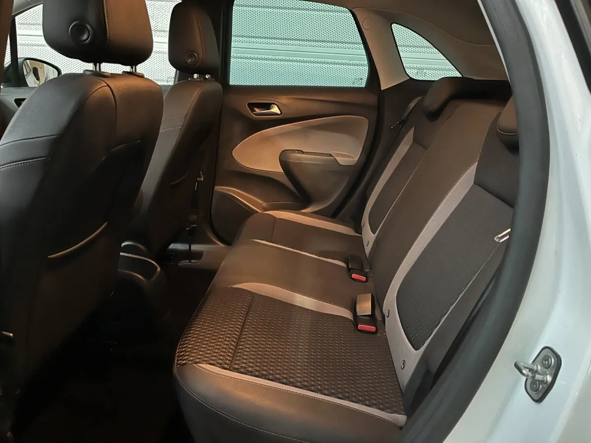Vue intérieure arrière côté droit de l’Opel Crossland X blanc, montrant la banquette bicolore noire et grise avec appuie-têtes.