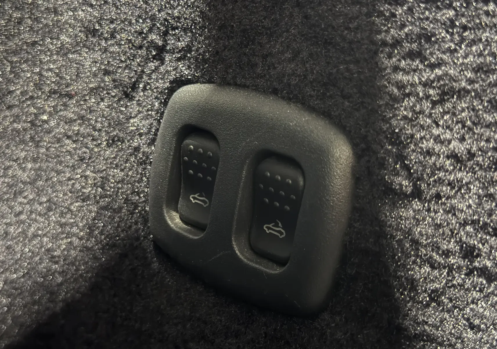 Gros plan sur les commandes d’ouverture du coffre et du capot dans l’habitacle d’une Alfa Romeo Spider bleu cabriolet 2006.