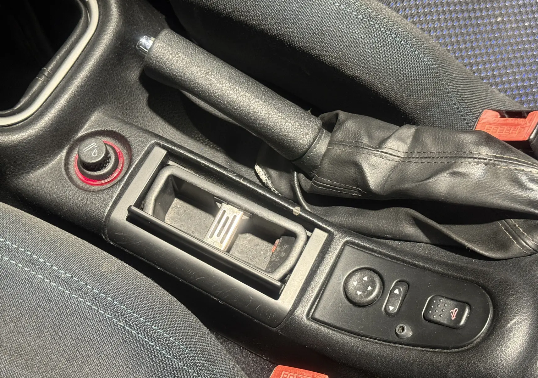 Gros plan sur la console centrale de l'Alfa Romeo Spider bleu 2006, montrant frein à main, commandes et tissu bleu des sièges.