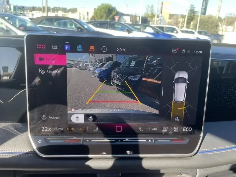 Vue de l'écran de recul du Volkswagen Tiguan 1.5 eHybrid gris métal, affichant l'aide au stationnement arrière en extérieur.