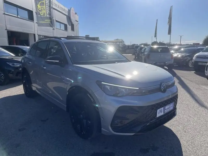 Volkswagen Tiguan 1.5 eHybrid R-line gris métal vu en 3/4 avant droit avec jantes noires et calandre marquée.