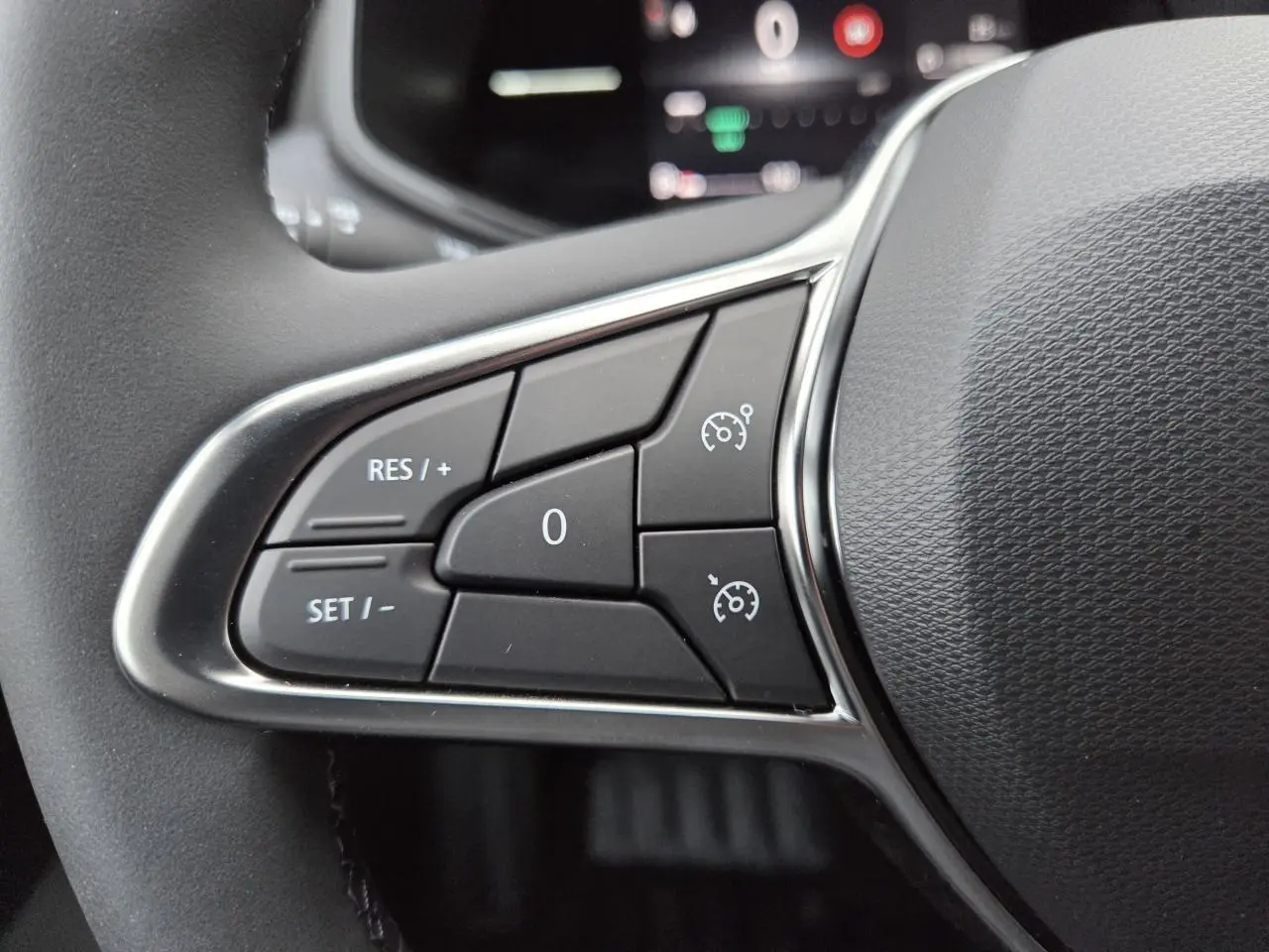 Gros plan sur les commandes de régulateur de vitesse au volant d’une Renault Clio V gris schiste métal.