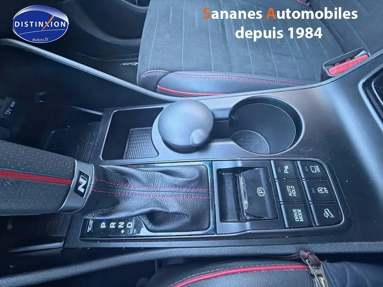 Vue rapprochée de la console centrale du Hyundai Tucson N Line 1.6 Hybrid, cuir noir avec surpiqûres rouges.