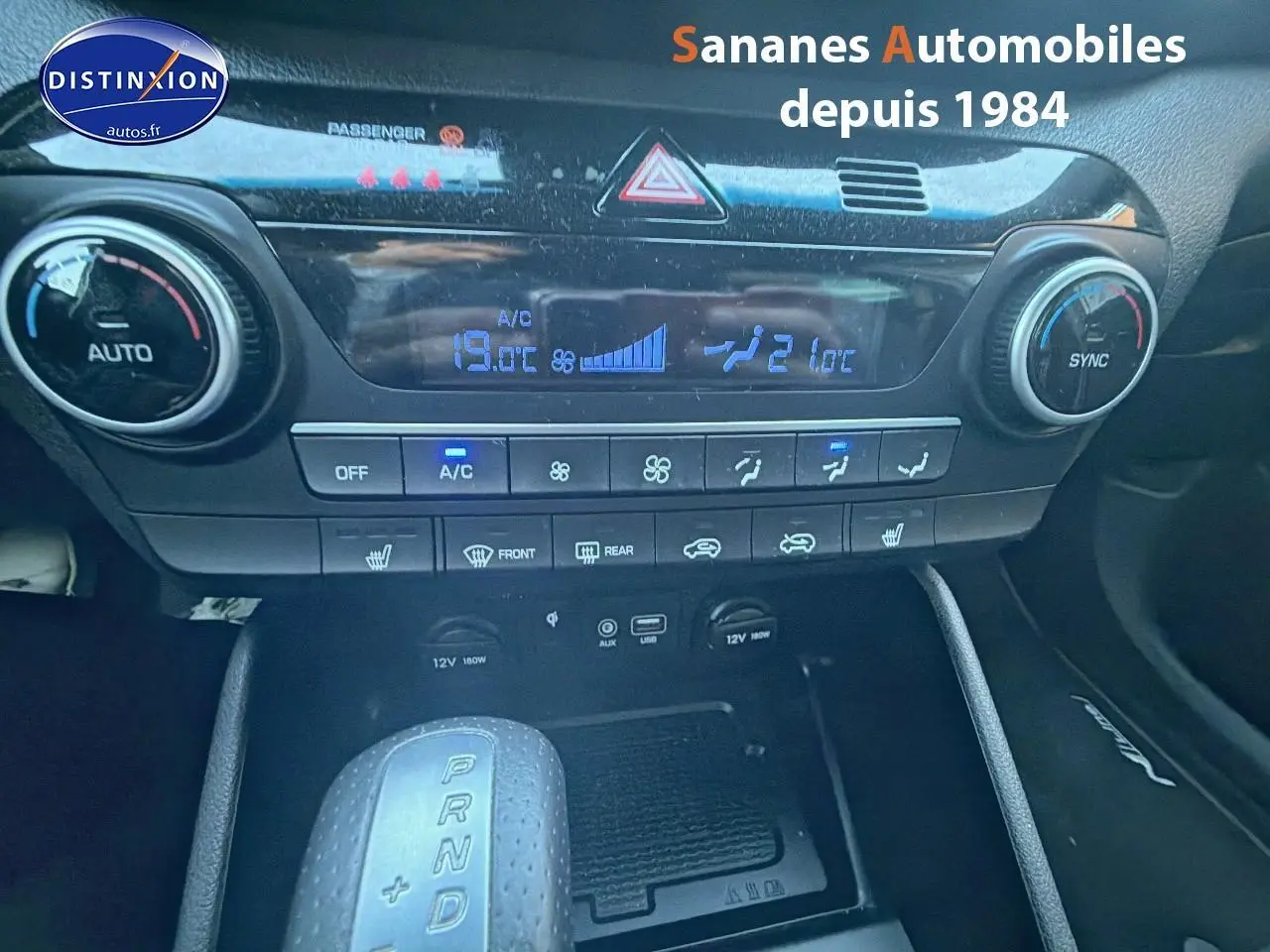 Vue rapprochée du tableau de bord et console centrale du Hyundai Tucson gris foncé, avec commandes climatisation et levier de boîte auto.