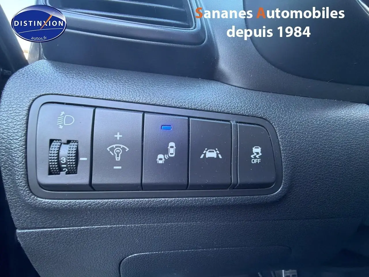 Vue rapprochée des commandes de sécurité et d’éclairage sur tableau de bord noir d’un Hyundai Tucson gris foncé.